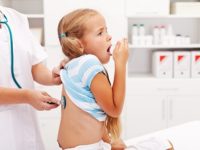 Little girl coughing at the doctor checkup - a health professional consulting her